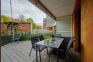 An inviting outdoor patio with a table, chairs, and a view of lush greenery.
