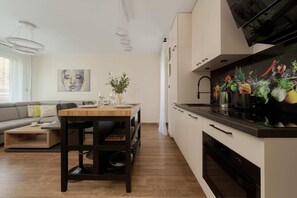 A modern open-plan dining area adjacent to the kitchen, featuring warm wooden furniture and contemporary decor.