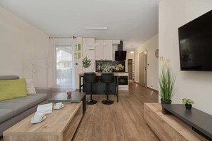 Another angle of the living room, showing the sofa, a wall-mounted TV, and stylish accessories.