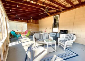 Outdoor screened in patio with seating and picnic table. 