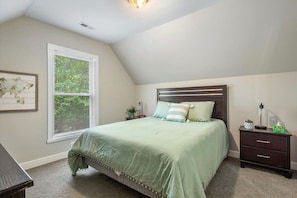 Primary bedroom on upper floor with queen-size bed and flat-screen Roku TV.