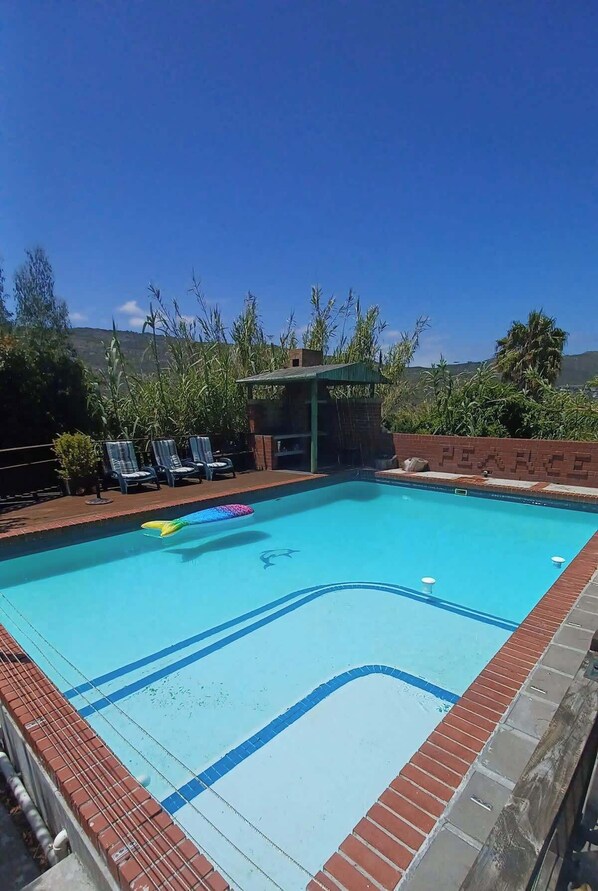 The pool area with lounger chairs and a braai area. 