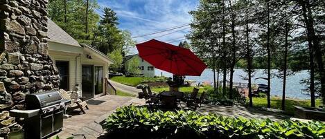 Outdoor patio with firepit, seating, huge umbrella, and Weber propane grill