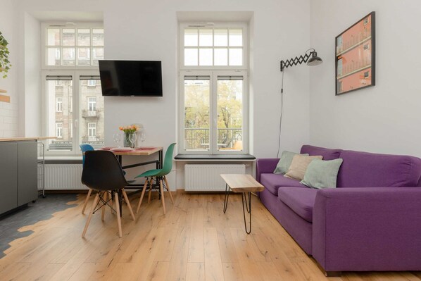 The spacious living room features a comfortable sofa bed and a flat-screen television.