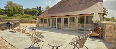 Large patio with chairs, outside sofa bed and charcoal BBQ