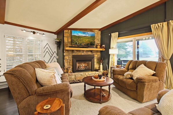 Cozy and welcoming, this open living area boasts a stunning stone fireplace and rustic wood-beam ceilings—an ideal setting for relaxing with loved ones or unwinding in comfort.