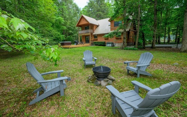 Cozy firepit area and hot tub on Scenic Creek cabin's lush green lawn.
