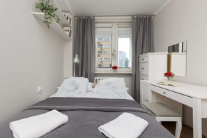 A bed with gray bedding, minimalist decor, bedside tables, and dark curtains adding a cozy touch.