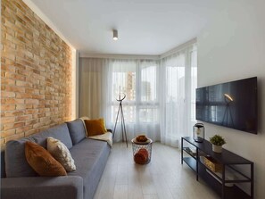 Stylish and cozy living room with a sofa bed, TV and access to balcony.