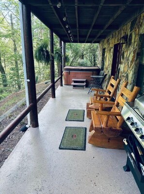 Patio with hot tub, chairs and BBQ grill.