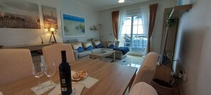 Living room with dining table, L-shaped sofa, coffee table, access to terrace