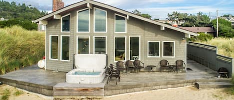 View of home facing the ocean. Hot tub and seating
