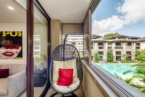 A hanging chair on the balcony is peacefully tucked away, ready for you to curl up and watch the clouds pass by over the pool.