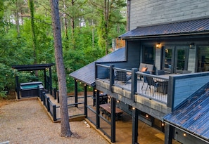This cabin's multi-level decks offer various outdoor experiences, from the cozy lounge area to the dining space below, all surrounded by the tranquility of tall pines.