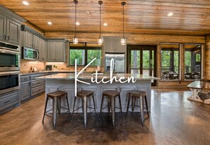 Prepare and enjoy meals in this spacious kitchen with modern appliances, a large island with seating, and an open layout that extends into a relaxing outdoor dining area.