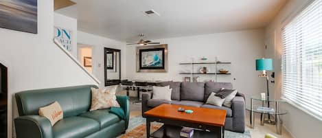 Open living space with comfortable couches, board games, indoor wood-burning fireplace, smart TV and dining area