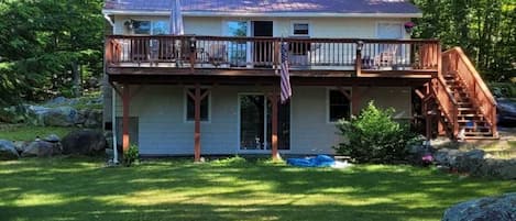 The house looking out on the water. Large deck, table, chairs, umbrella, grill.