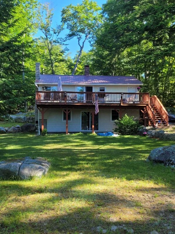 The house looking out on the water. Large deck, table, chairs, umbrella, grill.