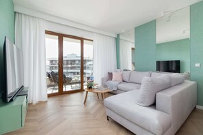 Stylish living room with corner sofa bed, TV and access to a furnished balcony.