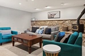 A basement living room provides a cozy hangout area for your group great for movie nights as you warm up by the wood-burning fireplace.