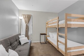 The second bedroom makes efficient use of its space with two twin mattresses on a wooden bunk bed and a futon sofa bed.