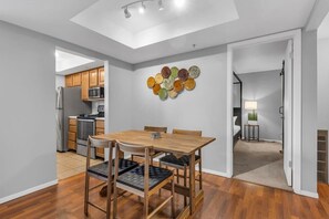 The dining area is centrally located to the kitchen and living room and features a wood table with seating for four underneath a box vault ceiling.