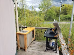 A summer kitchen with sink and prep area as well as a propane grill