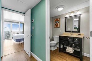 Step into this elegant bathroom featuring a modern vanity, warm lighting, and thoughtful details. With direct access to your cozy bedroom and balcony views, convenience meets coastal charm for a seamless stay.