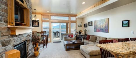 Experience the cozy living room, outfitted with plush seating, an expansive smart TV, and sliding patio doors that frame the breathtaking mountain vistas.
