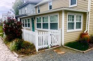 Fenced  front path opening  to driveway that  follows the side of the house. 