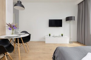 Double bed, TV and dining table with chairs in the studio.
