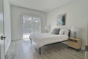 Master bedroom with queen bed, private bath, walk-in closet, and patio with olive orchard views.