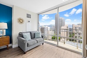 Gray sofa with chic decor, and expansive floor-to-ceiling windows showcasing city views 