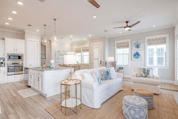 A beautifully designed open-concept living space featuring soft coastal tones, elegant décor, and ample seating for relaxation.