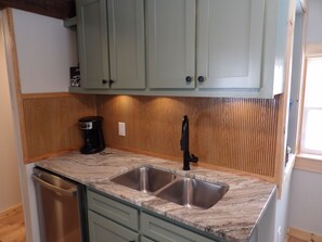 Kitchen sink with dishwasher and coffee pot.