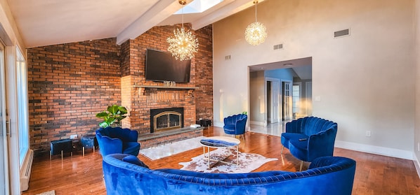 Living room with fireplace, TV, and floor-to-ceiling windows with mountain views