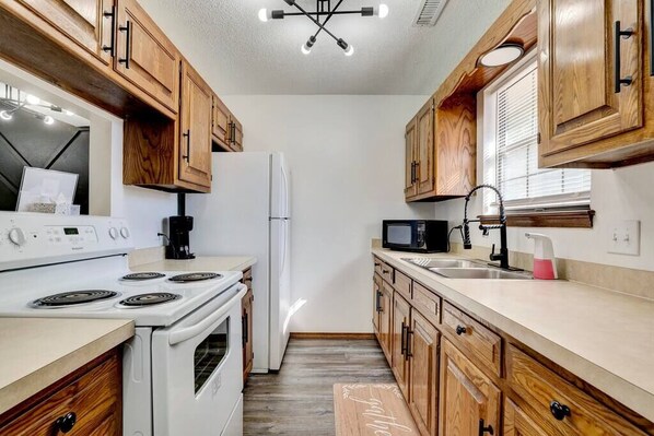 Full galley kitchen with electric range, microwave and full size fridge