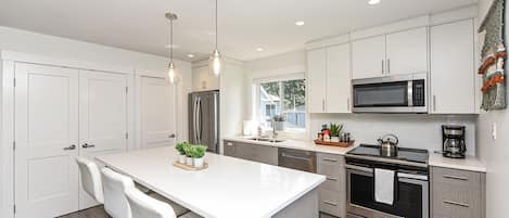 Modern kitchen with stainless steel appliances and quartz countertops. 