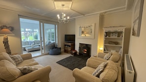 Living room with wood burning stove and adjacent sunroom