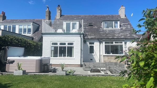 The balcony overlooks the patio with hot tub and extensive south facing garden