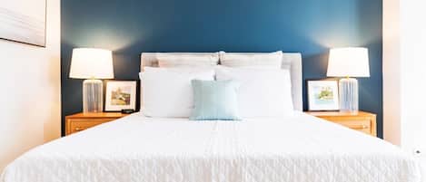 Comfy Queen size bed with stylish lamp shades and calming blue wall