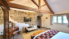 Beautiful bedroom with vaulted ceiling and exposed stone wall