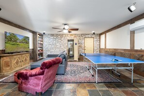 media room with sofa bed, TV, and a ping pong table.