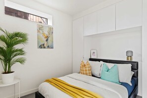 A bedroom with a double sized bed & plush pillows.
