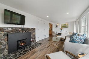 Living room with woodstove and fireplace open to dining area