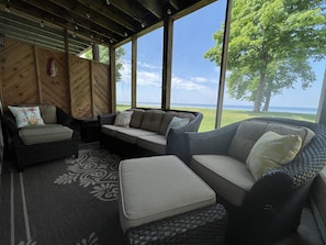 Screen porch overlooking the lake with comfortable wicker furniture.