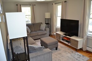 Cozy, light filled, living room with large firestick TV, books, and board games.