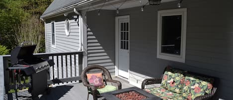 Outdoor deck extending off the back, with fire pit, grill, and ambient lighting.