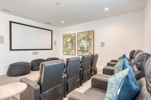 Movie room with theater seating and a huge projector screen.