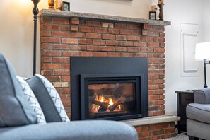 Cozy living room with a comfy couch and loveseat, perfect for relaxing after a day of adventure. Enjoy the warmth of the decorative propane fireplace and stream your favorite shows on the Smart TV for a perfect night in! | Arrowhead Lake
